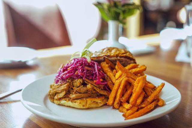Criollo Restaurant's Hot Pulled Pork Sandwich, dressed with marinated red cabbage and onions, toasted onion roll and horseradish caraway sauce