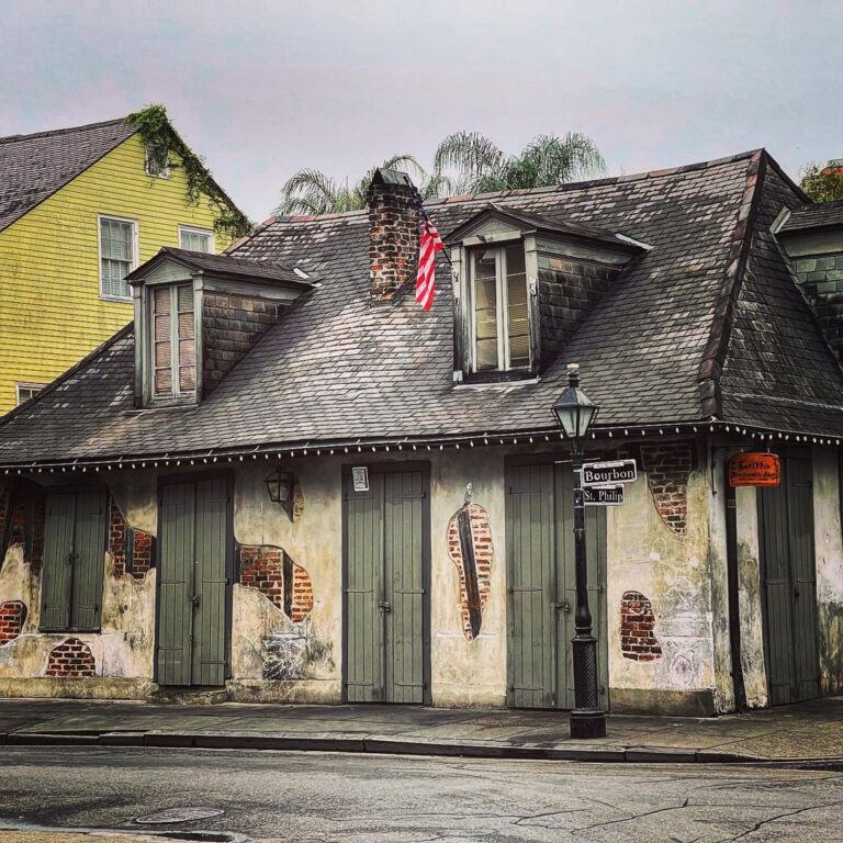 View of Lafitte's Blacksmith Shop building with exposed brick, green shutters, and famous slate roof.