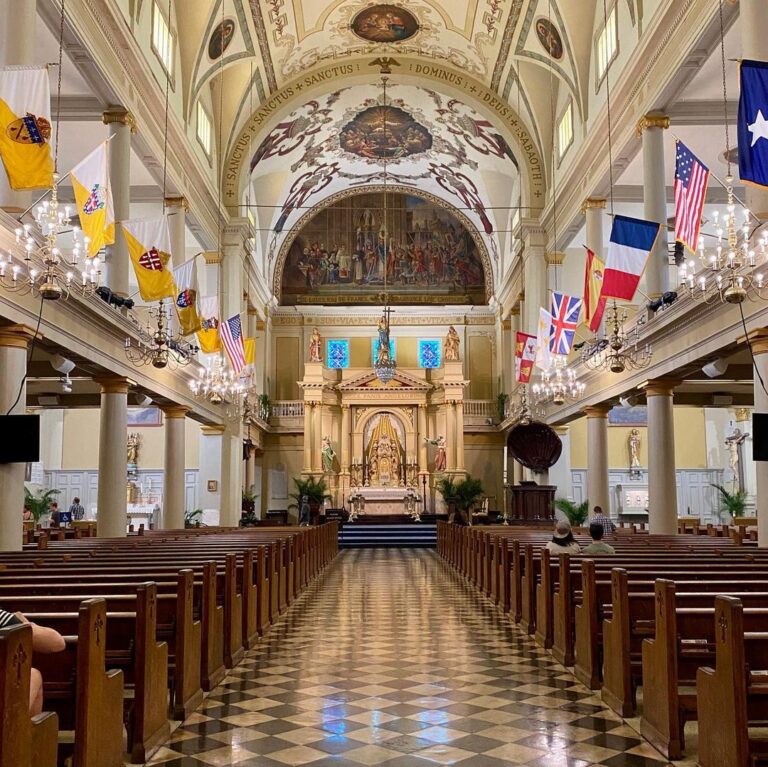 Inside view of the opulent cathedral, showing dark wooden pews on either side of the aisle, and the altar in the distance