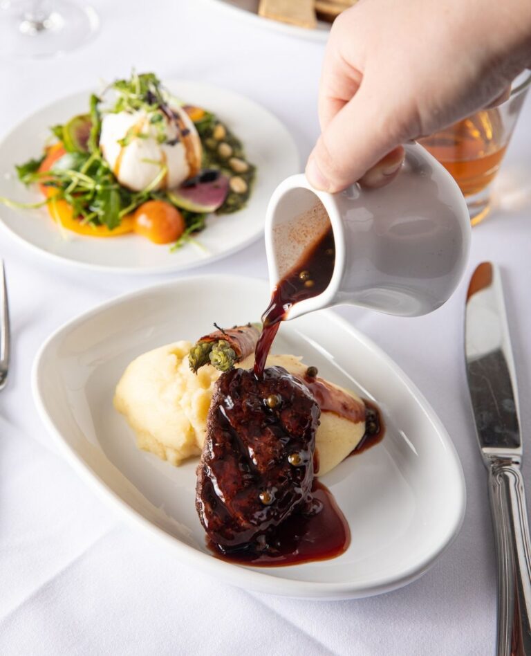 A tablescape at Criollo Restaurant in New Orleans with gravy being poured over a dish